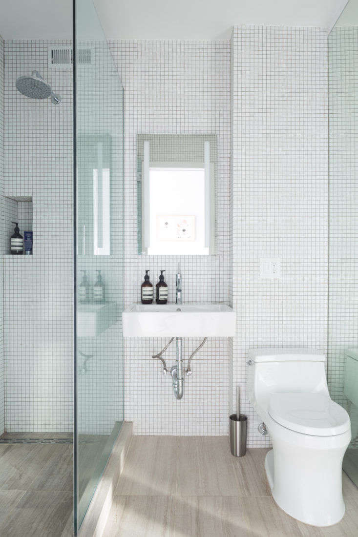 In the bathroom, an inset niche corrals shower essentials. Note also how the continuous flooring and wall tiles throughout make the room feel bigger and more cohesive.