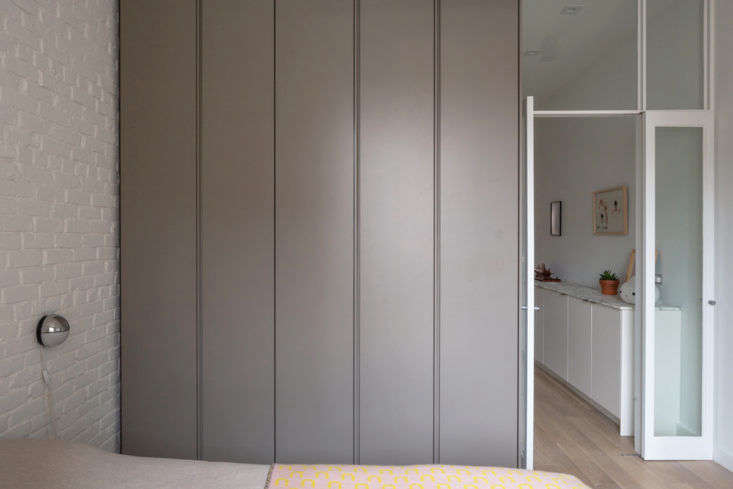 A wardrobe alongside the bed looks sleek when closed. Without so much as door pulls, it looks more like a wall than something to be opened.