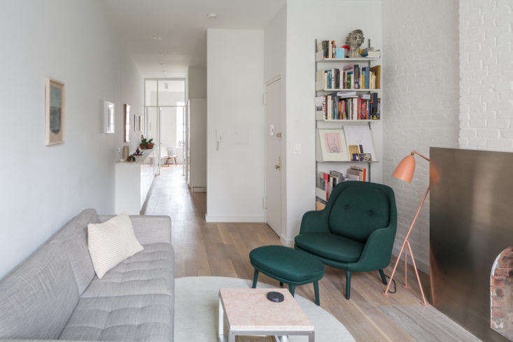 Looking toward the new walk-through kitchen (which was formerly walled off from the rest of the space) and the bedroom beyond. The duo had the wood floor laid lengthwise, rather than width-wise, to emphasize the length of the apartment.
